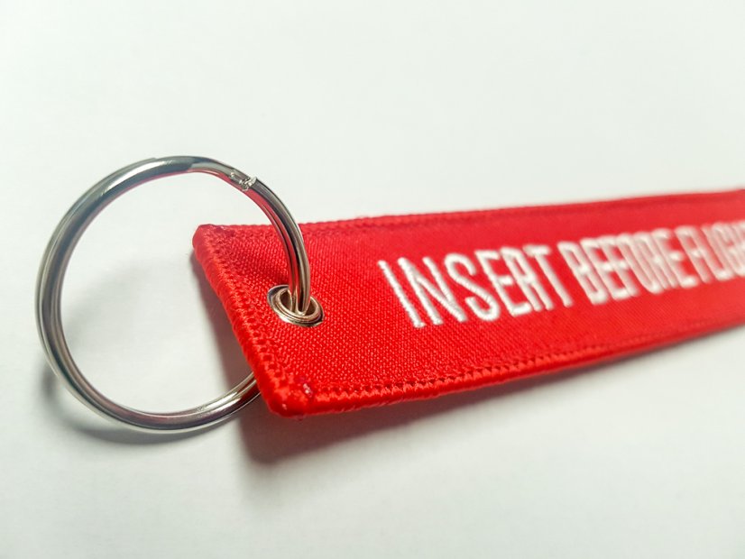 Přívěsek na klíče "Insert before flight"